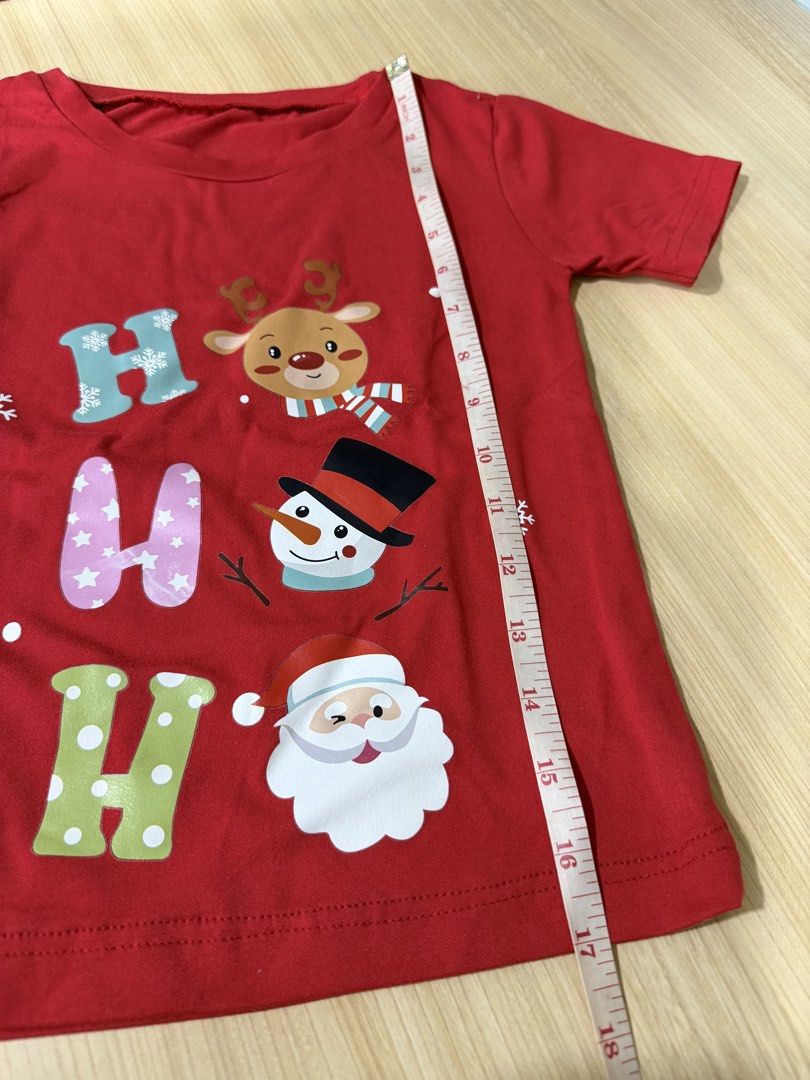 Christmas Red T-shirt (Category: Babies & Kids Fashion) located in Mandaluyong City. Submitted by jpc0708 (Listing ID 1437135573, Image 2). Description: - Red Christmas t-shirt - Features "HO HO HO" design with reindeer, snowman, and Santa Claus - Short sleeves - Round neckline - Measurements: Approximately 17 inches length x 13 inches width - Plain red back.