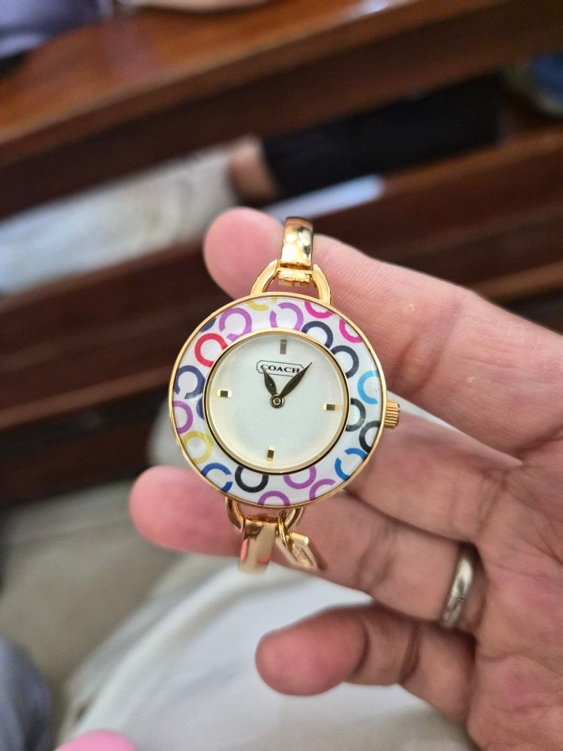 Coach Women's Bangle Watch (Category: Looking For) located in Mandaue City. Submitted by chuchi152615 (Listing ID 1437040625, Image 1). Description: - Coach women's watch - stainless / water resistant - Gold-tone bangle strap - White dial with gold-tone hands and markers - Colorful circle pattern on the dial - Coach logo and '2765' on the back - Includes Coach tag.