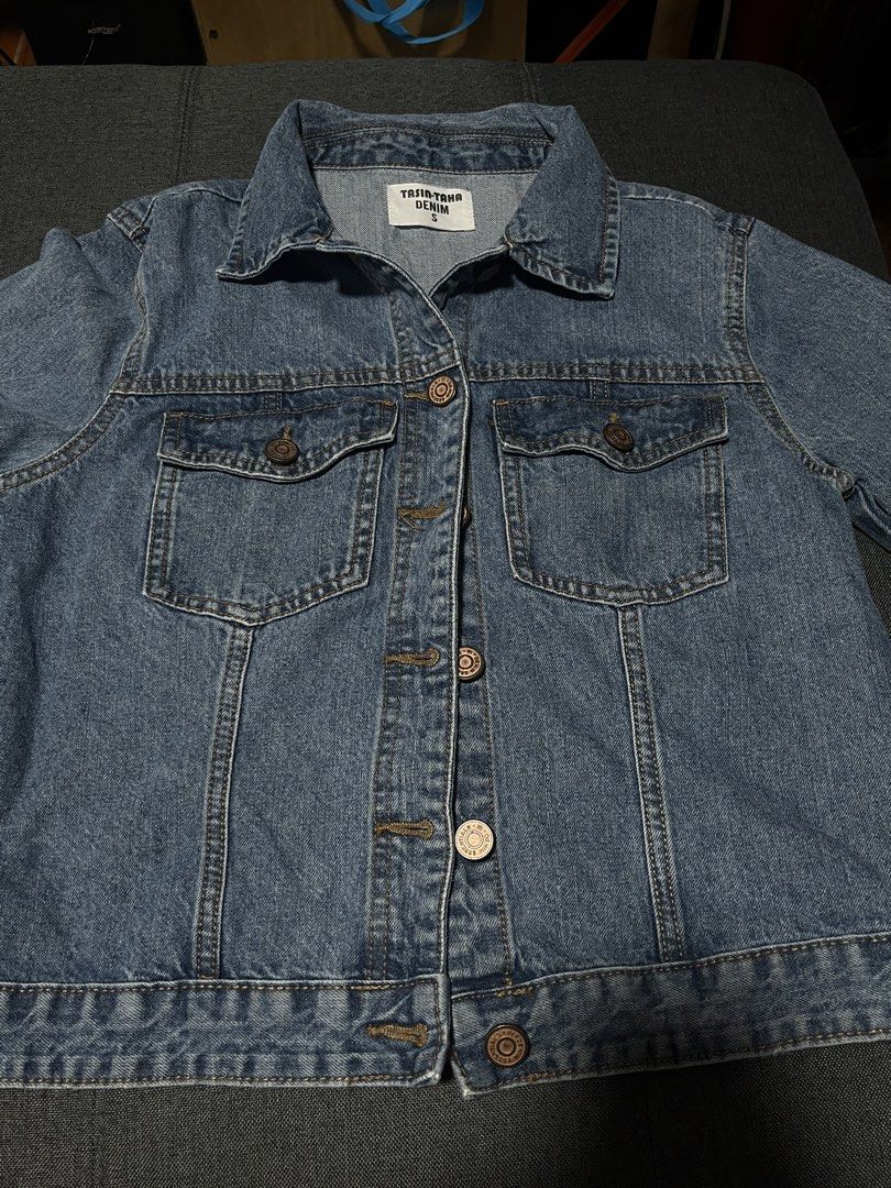 Denim Jacket (Category: Coats, Jackets and Outerwear) located in Marikina City. Submitted by d.clutters (Listing ID 1437108235, Image 1). Description: - Brand: Tria-Trio Denim - Size: L - Style: Classic denim jacket - Color: Medium blue wash - Features: Collared neckline, button closures, two chest pockets - Fit: Standard - Design: Simple back - Perfect for everyday wear.