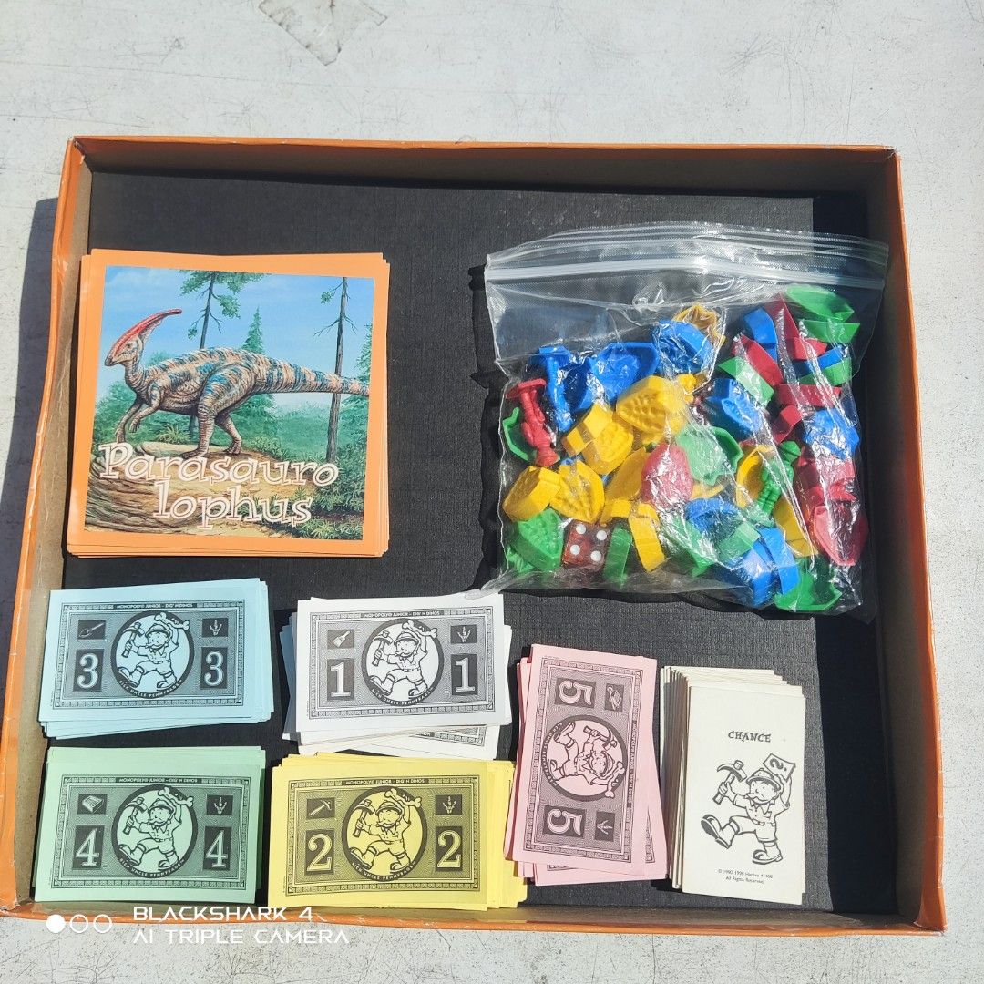 Monopoly Junior Dig 'n Dinos Board Game (Category: Board Games & Puzzles) located in Bugallon. Submitted by ariel013 (Listing ID 1437054264, Image 3). Description: - Monopoly Junior Dig 'n Dinos board game - For 2-4 players - Ages 5+ - Features dinosaur-themed property cards - Includes game board, cards, play money, game pieces, and dice - Box shows some wear.