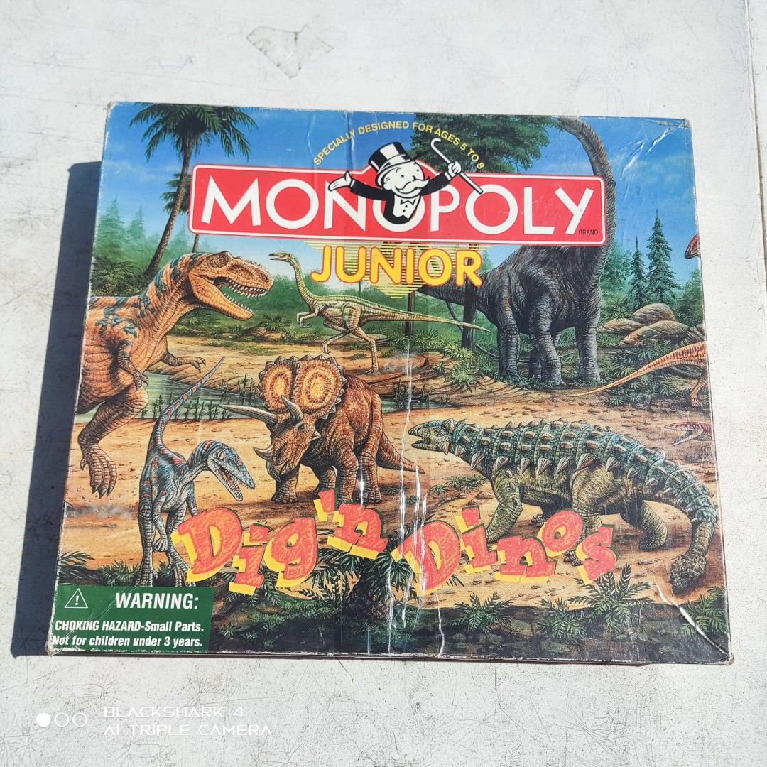 Monopoly Junior Dig 'n Dinos Board Game (Category: Board Games & Puzzles) located in Bugallon. Submitted by ariel013 (Listing ID 1437054264, Image 1). Description: - Monopoly Junior Dig 'n Dinos board game - For 2-4 players - Ages 5+ - Features dinosaur-themed property cards - Includes game board, cards, play money, game pieces, and dice - Box shows some wear.