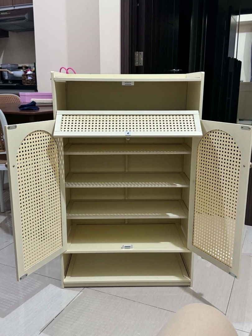 Rattan Style Shoe Cabinet (Category: Everything Else Others) located in Manila. Submitted by jezm. (Listing ID 1437186661, Image 2). Description: - Rattan-style shoe cabinet - Two doors - Multiple shelves for shoe storage - Top drawer - Open bottom shelf - Light cream color - Made of wood or similar material.