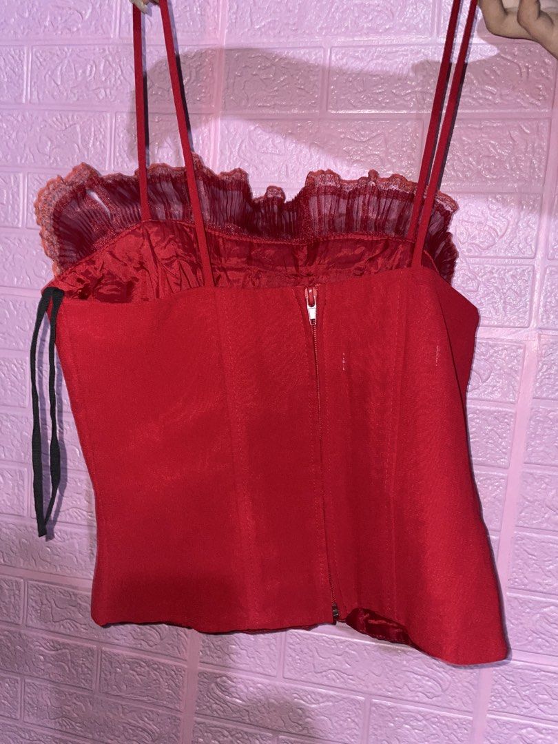Red Corset Top with Ruffle Detail (Category: Sleeveless) located in Quezon City. Submitted by radiusmile (Listing ID 1437113489, Image 2). Description: - Red corset top - Spaghetti straps - Ruffle neckline detail - Fitted silhouette - Back zipper closure - Vibrant red color - Smooth, satin-like material.