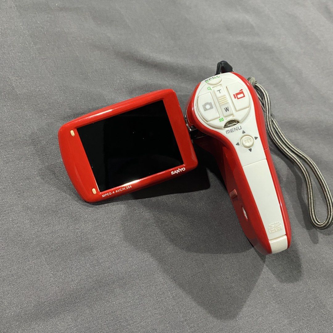 Sanyo Xacti Digital Camcorder (Category: Cameras) located in Rizal. Submitted by shop.ai (Listing ID 1437056170, Image 3). Description: - Sanyo Xacti digital camcorder - Color: Red and White - Built-in screen and control buttons - Includes battery pack and charger - Features a hand strap - Compact and portable for video recording issues: - missing a button but can make it work by putting a pin or something pointy. - battery is charged but won’t o