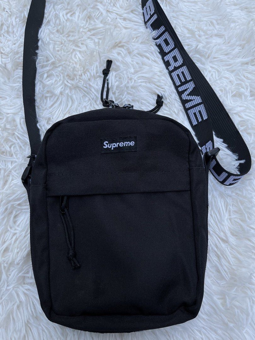 Supreme Shoulder Bag Black SS18 (Category: Luxury Bags & Wallets) located in Davao. Submitted by streetsight (Listing ID 1437115644, Image 2). Description: - Black Supreme shoulder bag - White logo strap - Front zip pocket - Main compartment - Supreme logo on front - Zipper closure - Supreme logo on strap - Durable, possibly nylon material.