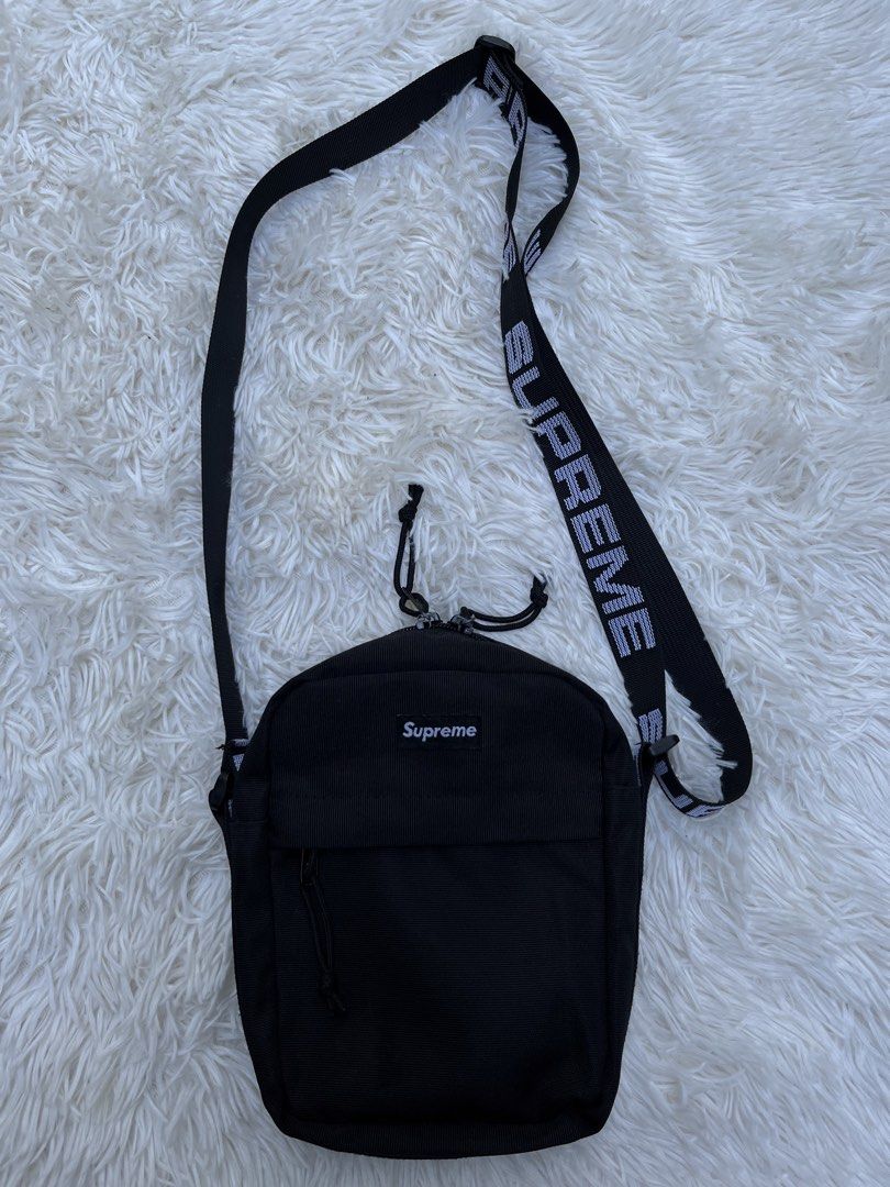 Supreme Shoulder Bag Black SS18 (Category: Luxury Bags & Wallets) located in Davao. Submitted by streetsight (Listing ID 1437115644, Image 1). Description: - Black Supreme shoulder bag - White logo strap - Front zip pocket - Main compartment - Supreme logo on front - Zipper closure - Supreme logo on strap - Durable, possibly nylon material.