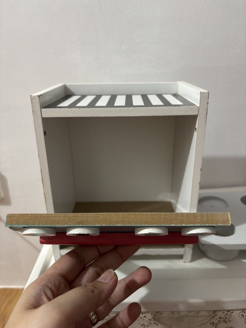 Wooden Toy Kitchen Stove (Category: Kids Toys) located in Bulacan. Submitted by lmsdeclutteringcorner (Listing ID 1437025151, Image 2). Description: - Wooden toy kitchen stove - Teal front with red accents - Striped top - Four black knobs - Separate white stovetop with burner circles - Open oven door - Made of wood -ISSUE: hindi po nala-lock yung door ng oven -with sign of usage -yung kasama free ko na lang, not sure if pang cupcake sya eh hehe🤭