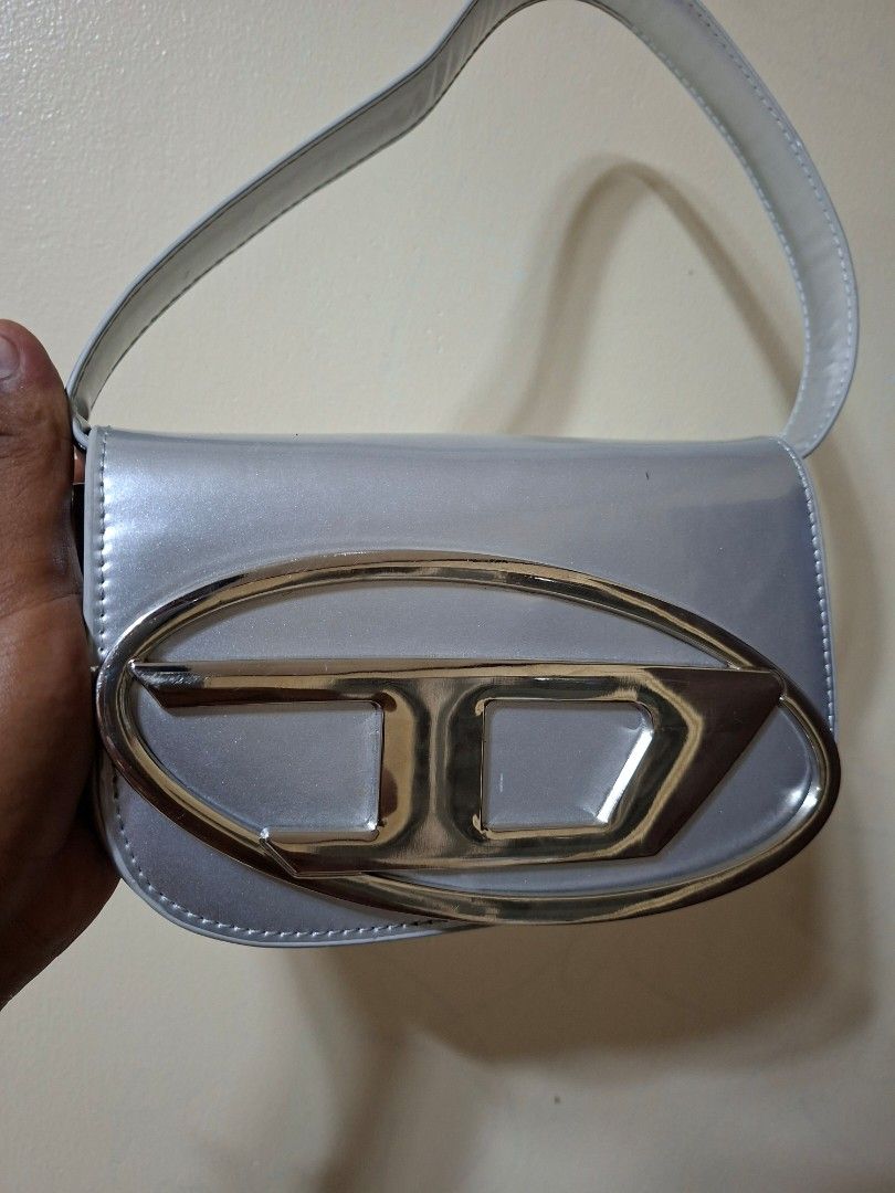 1DR Deisel Shoulder bag (Category: Luxury Bags & Wallets) located in Santiago. Submitted by dc_daily_thrift (Listing ID 1437376174, Image 3). Description: - 1DR Deisel Shoulder bag - Shoulder strap included - Magnetic closure - Shiny, possibly patent, material - Rectangular shape with rounded edges - Silver interior .
