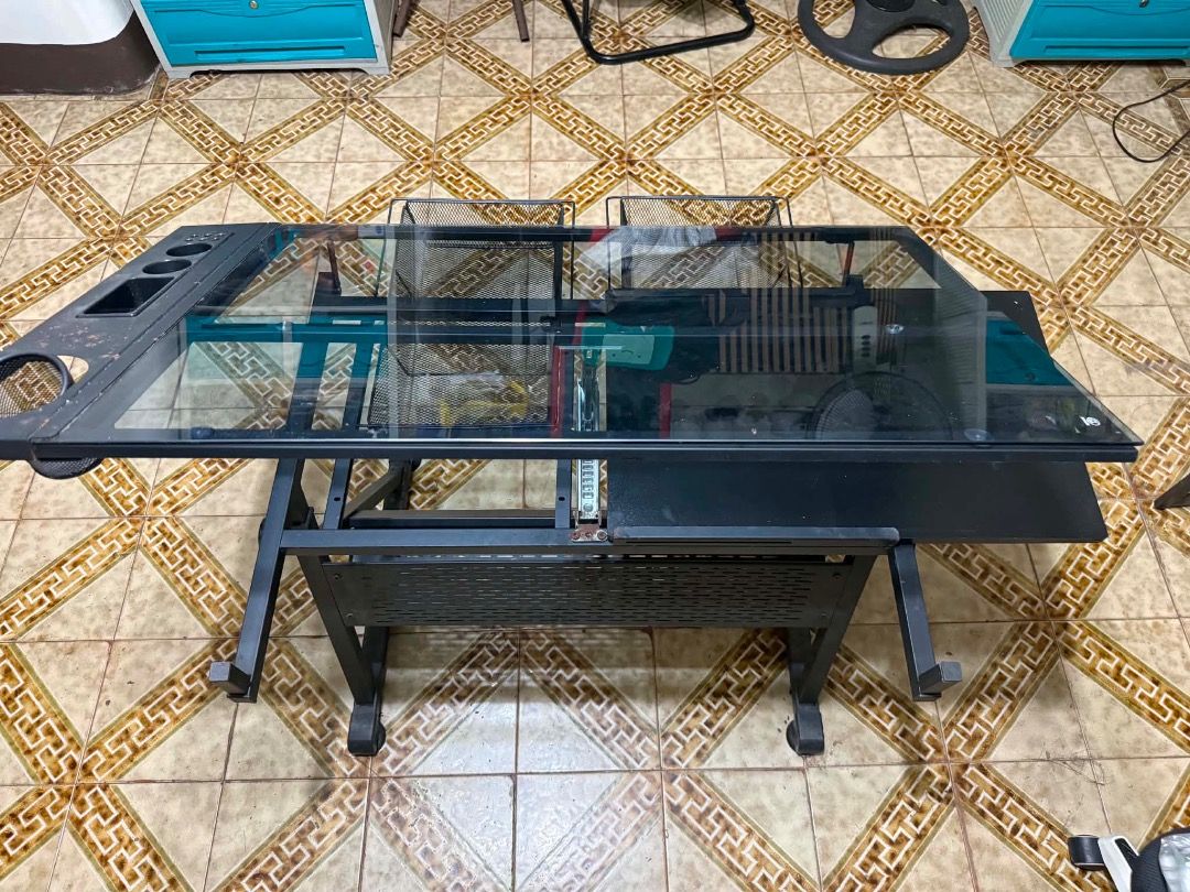 Black Glass Top Drafting Desk for Architect (Category: Tables & Sets) located in Manila. Submitted by memos_ (Listing ID 1437242606, Image 2). Description: - Black drafting desk - Glass top - Pull-out side table - Built-in storage and wire mesh baskets - Sturdy metal frame - Wheels for easy movement - Ideal for drawing and creative work.