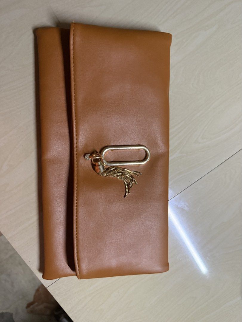 Brown Clutch Bag with Magnetic Closure (Category: Clutches) located in Quezon City. Submitted by cut_rate_shop (Listing ID 1437326878, Image 1). Description: - Brown clutch bag - Magnetic closure - White fabric lining - Rectangular shape - Smooth material - Suitable for various occasions - Never used.