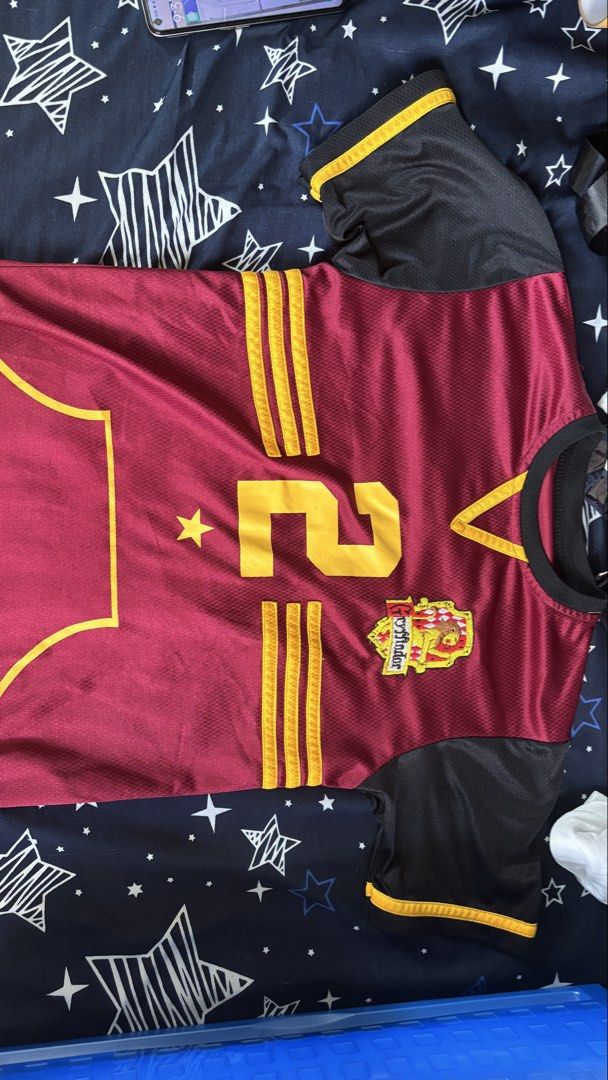 College Jersey - Maroon and Gold (Category: Tshirts & Polo Shirts ) located in Cainta. Submitted by kd0529 (Listing ID 1437211635, Image 1). Description: - Maroon and gold jersey - Number 2 on front and back - Features a star and college crest - Black sleeves with gold trim - "KEEPER" printed on the back - V-neck design.