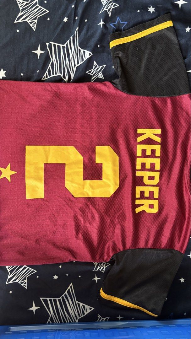 College Jersey - Maroon and Gold (Category: Tshirts & Polo Shirts ) located in Cainta. Submitted by kd0529 (Listing ID 1437211635, Image 2). Description: - Maroon and gold jersey - Number 2 on front and back - Features a star and college crest - Black sleeves with gold trim - "KEEPER" printed on the back - V-neck design.