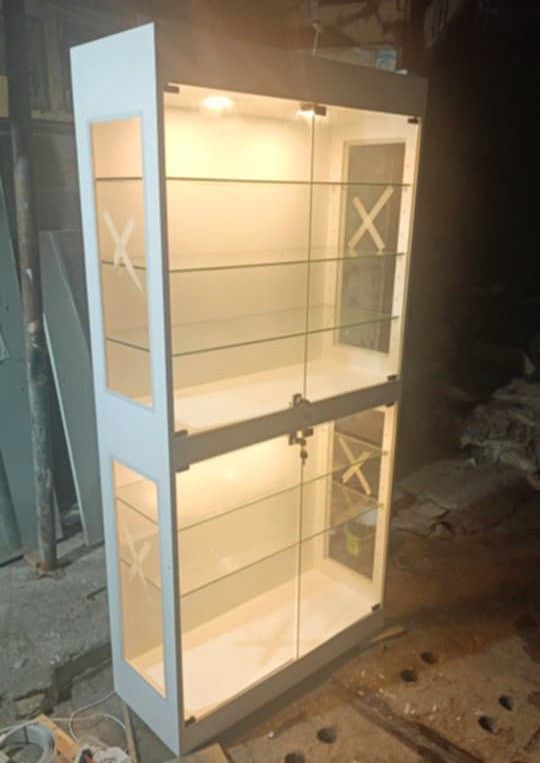 Glass Display Cabinet with Lights (Category: Shelves, Cabinets & Racks) located in Manila. Submitted by ronav25916562 (Listing ID 1437306499, Image 1). Description: - Elegant glass display cabinet - Two sections with multiple shelves - Built-in lighting - White frame - Glass doors - Includes a lock - Ideal for collectibles and valuables - Suitable for home or retail Made to order.