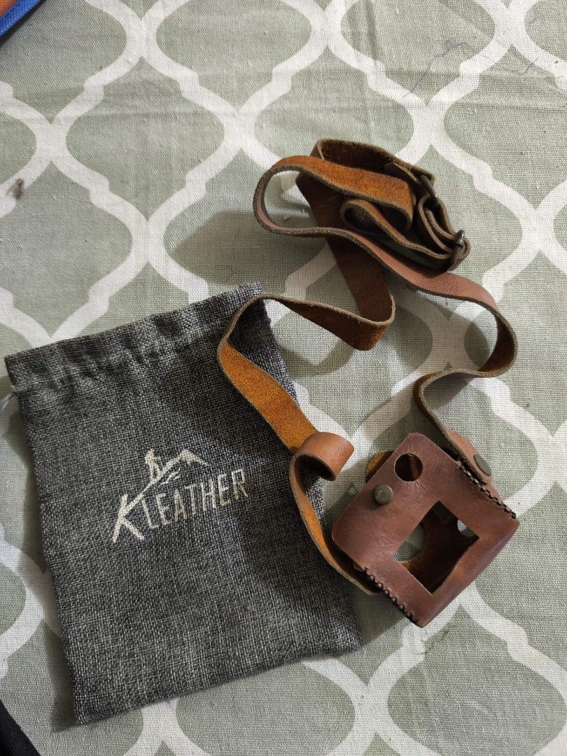 K Leather Camera Case with Strap (Category: Camera Bags & Carriers) located in Taguig. Submitted by juliestjuly (Listing ID 1437338504, Image 1). Description: - Genuine leather camera case -for GoPro hero 3/4 - Matching adjustable strap - Brown case with black stitching - Metal button closures - Square lens opening and two circular openings - Includes gray drawstring pouch with "K Leather" logo.