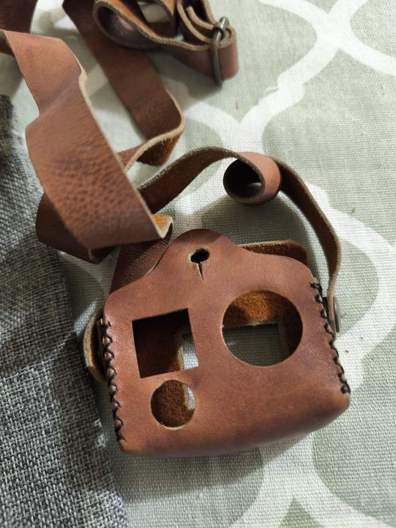 K Leather Camera Case with Strap (Category: Camera Bags & Carriers) located in Taguig. Submitted by juliestjuly (Listing ID 1437338504, Image 3). Description: - Genuine leather camera case -for GoPro hero 3/4 - Matching adjustable strap - Brown case with black stitching - Metal button closures - Square lens opening and two circular openings - Includes gray drawstring pouch with "K Leather" logo.