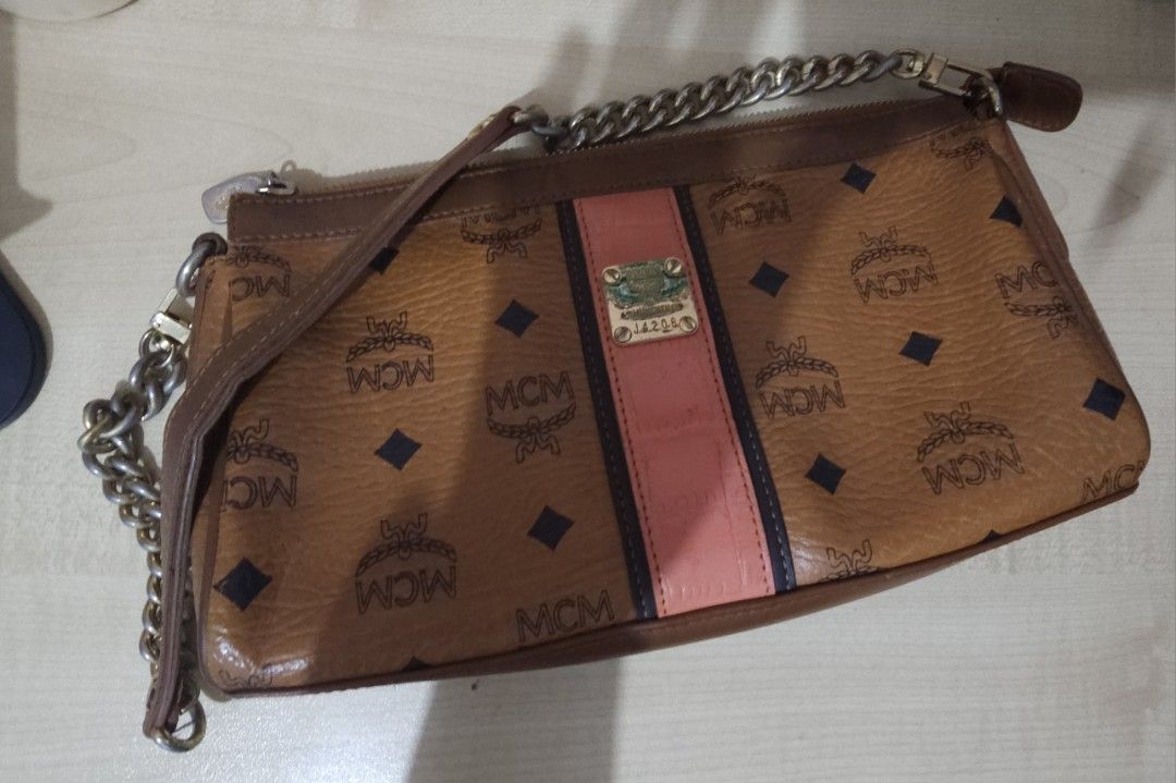 MCM Visetos Chain Clutch Bag (Category: Luxury Bags & Wallets) located in Batangas. Submitted by finestonesandfindsph (Listing ID 1437317225, Image 1). Description: - MCM Visetos chain clutch bag - Iconic MCM logo print with a pink stripe - Gold-tone metal logo plate - Perfect for everyday or special events.