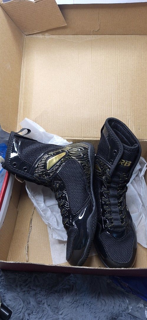 RB Boxing Shoes Black size 37 (Category: Combat Sports) located in Manila. Submitted by chavezmade78698 (Listing ID 1437365116, Image 3). Description: - Black boxing shoes with gold accents - Features "RB" brand logo - "BOXING" text visible on the side - Shiny, patent leather-like toe and heel - Includes original box and tissue paper.