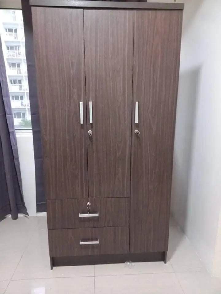 Wooden Wardrobe with Drawers (Category: Shelves, Cabinets & Racks) located in Manila. Submitted by lykcacamacho07 (Listing ID 1437287826, Image 2). Description: - Dark brown wooden wardrobe - 3 doors - 2 drawers - Includes hanging rod - Features shelves for storage - Silver handles - Ideal for bedroom use.