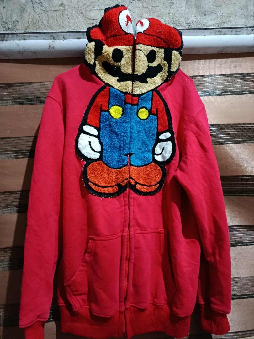 Baby Milo Mario Hoodie (Category: Hoodies) located in Bolinao. Submitted by willaskyle19427 (Listing ID 1437420918, Image 1). Description: - Red hoodie with a large Mario design on the front. - Features a Baby Milo Mario graphic on the back. - Full zip closure. - Hood designed like a Mario hat. - Made of soft material. - Includes a kangaroo pocket. issue - not working zipper need repair.