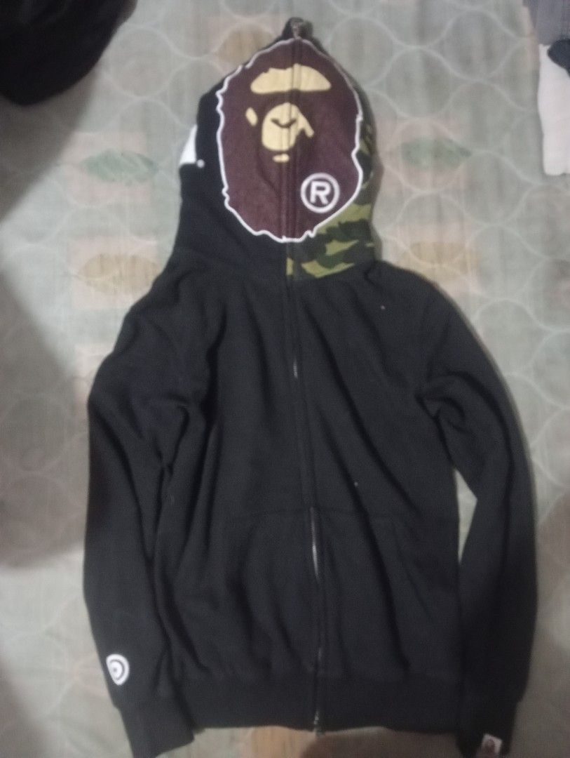 BAPE Full Zip Hoodie (Category: Hoodies) located in Bolinao. Submitted by willaskyle19427 (Listing ID 1437420550, Image 1). Description: - Black BAPE full zip hoodie - Camo-patterned hood - Iconic BAPE ape head on hood - BAPE logo on sleeves - White logo on sleeve - Visible tag fake/legit check the tag issue:may puti puti .