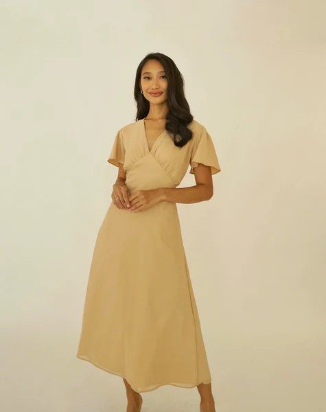 Beige Midi Dress (Category: Dresses) located in Muntinlupa City. Submitted by em_prelovedx (Listing ID 1437545909, Image 3). Description: - Beige midi dress - V-neckline - Flutter sleeves - Flared skirt - Tie-back detail for adjustable fit - Perfect for special occasions .