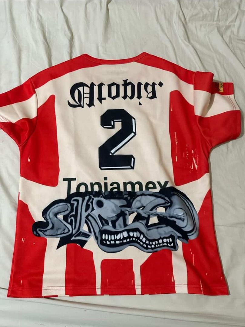 cactus jack UTopia Maximo soccer football Jersey size medium (Category: Shirts) located in Quezon City. Submitted by dune--closet (Listing ID 1437512702, Image 2). Description: - Red and white striped jersey - Features "MAXIMO" on the front - "Atobia" and "2" on the back - Includes a graphic design at the bottom - Round neck and short sleeves - Size: M.