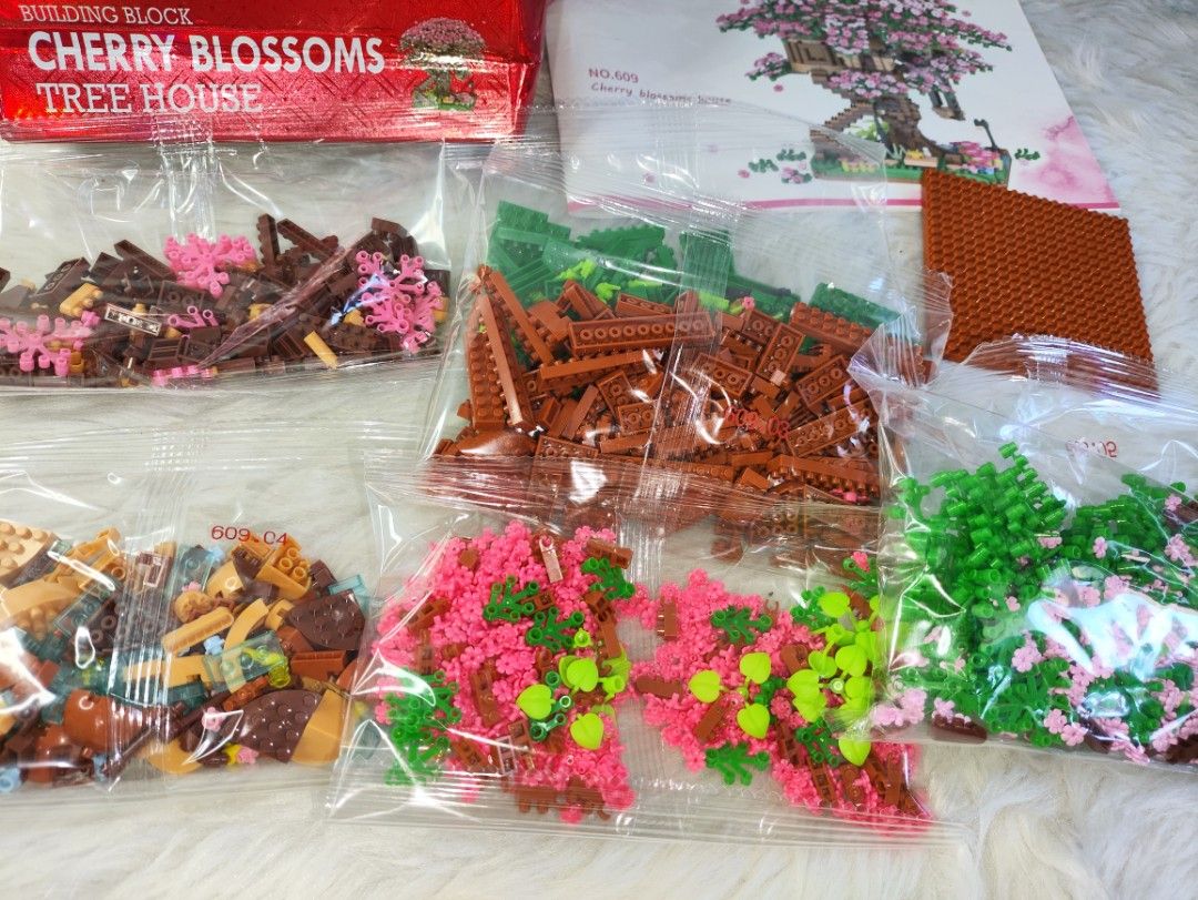 Cherry Blossoms Tree House Building Block Set (Category: Toys & Games) located in Cavite. Submitted by tinetaclesss (Listing ID 1437444386, Image 2). Description: - Cherry Blossoms Tree House building block set. - Includes various colored blocks. - Comes with a detailed instruction manual. - Multiple sealed bags of blocks included (all pieces present). - Complete set, ready for assembly. - Box shows the finished model..