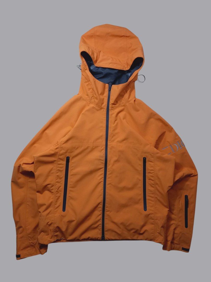 Dior Orange Nylon Hooded Jacket (Category: Coats, Jackets and Outerwear) located in Quezon City. Submitted by davidso682 (Listing ID 1437411349, Image 2). Description: - Dior orange hooded jacket - Full zip closure - Two zipped front pockets - Dior logo on sleeve - Black lining - Dior logo pattern on inside hem - Adjustable hood with drawstrings - Black zipper.