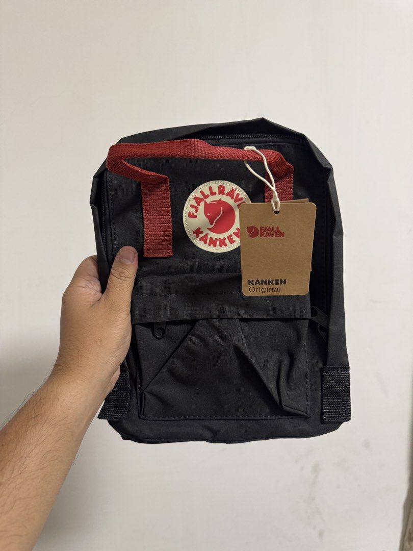 Fjallraven Kanken Mini Backpack (Category: Backpacks) located in Valenzuela. Submitted by fairythrift (Listing ID 1437513487, Image 2). Description: Fjallraven Kanken Original backpack - Classic black with red straps - Features the Fjallraven logo - Includes original tag and pamphlet - Zipper closure - Adjustable straps - Top handle - Interior label with Fjallraven logo and text.