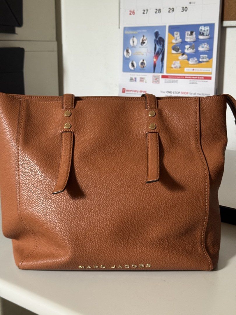 Marc Jacobs Jordan Logo Leather Brown Tote Bag (Category: Luxury Bags & Wallets) located in Muntinlupa City. Submitted by daisydosephh (Listing ID 1437552051, Image 1). Description: Marc Jacobs Jordan Studded Leather Tote NWOT Cognac Brown Pebbled Work Laptop The Perfect Everyday Power Bag > Elevate your professional wardrobe with this sophisticated Marc Jacobs Jordan Tote. Crafted from premium, heavy-grain pebbled leather, this extra-large tote 