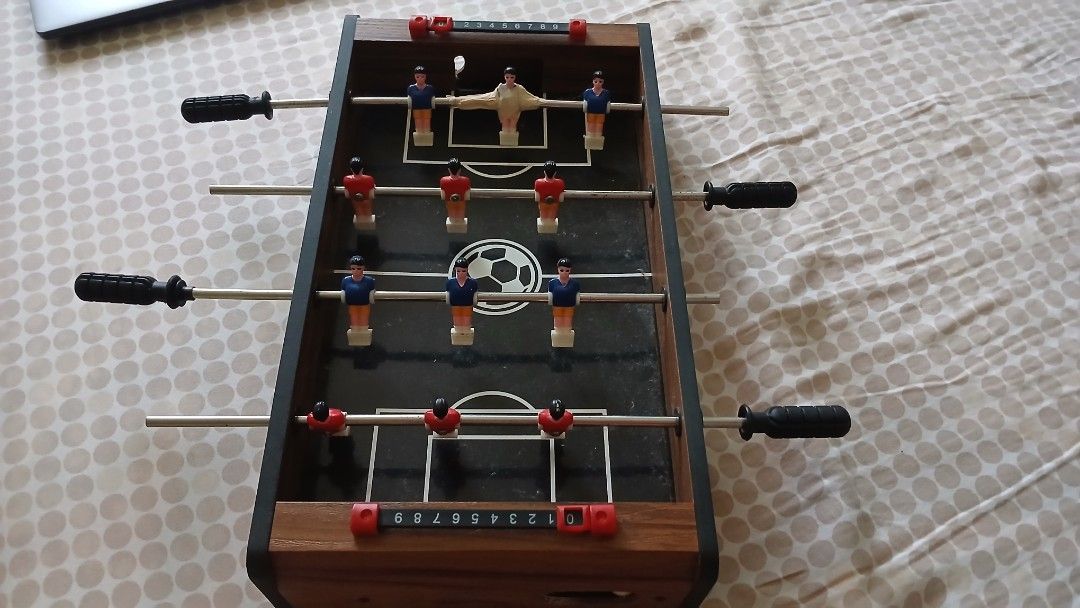 MD Sports Mini Foosball Table (Category: Board Games & Puzzles) located in Imus. Submitted by dahdahlicious (Listing ID 1437455037, Image 2). Description: - MD Sports mini foosball table - Black playing surface with soccer ball graphic - Includes red and blue player figures - Features score trackers and handles - Wooden frame - Model: T17200Y22001 - Made in China.