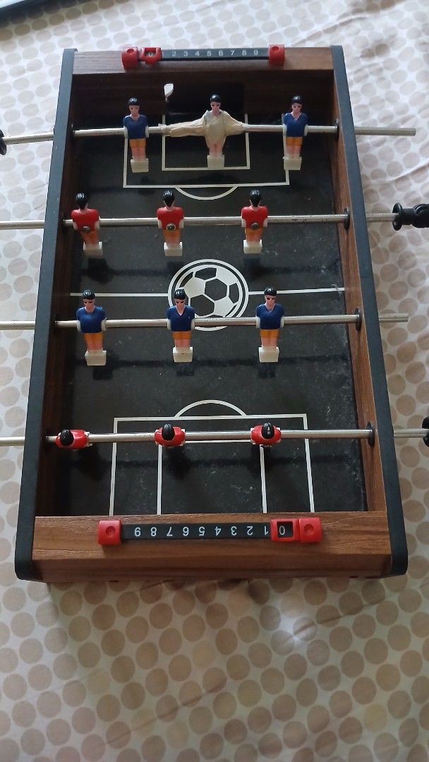 MD Sports Mini Foosball Table (Category: Board Games & Puzzles) located in Imus. Submitted by dahdahlicious (Listing ID 1437455037, Image 1). Description: - MD Sports mini foosball table - Black playing surface with soccer ball graphic - Includes red and blue player figures - Features score trackers and handles - Wooden frame - Model: T17200Y22001 - Made in China.