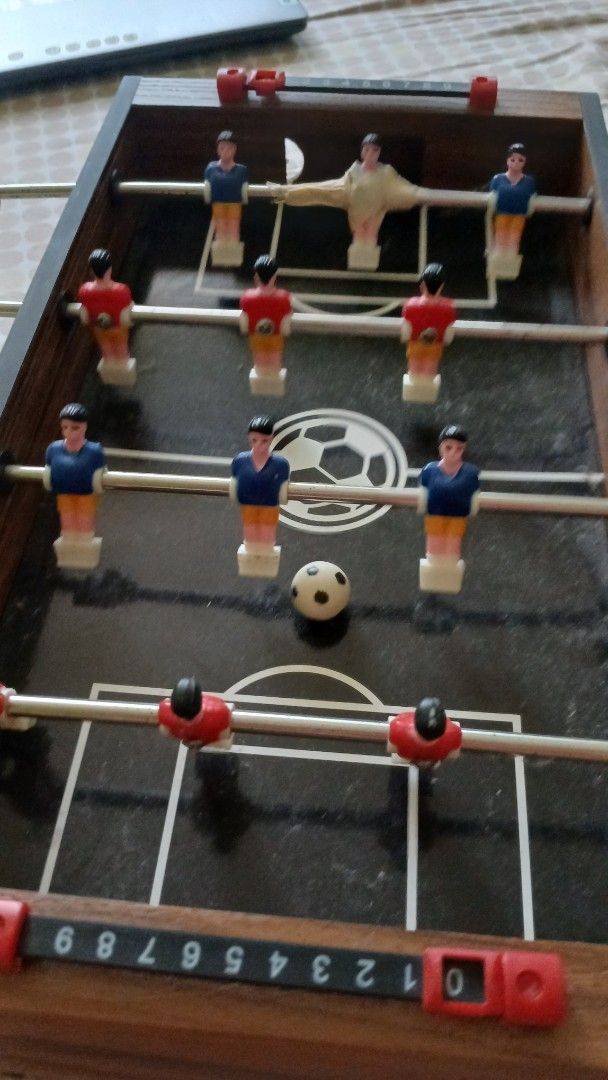 MD Sports Mini Foosball Table (Category: Board Games & Puzzles) located in Imus. Submitted by dahdahlicious (Listing ID 1437455037, Image 3). Description: - MD Sports mini foosball table - Black playing surface with soccer ball graphic - Includes red and blue player figures - Features score trackers and handles - Wooden frame - Model: T17200Y22001 - Made in China.
