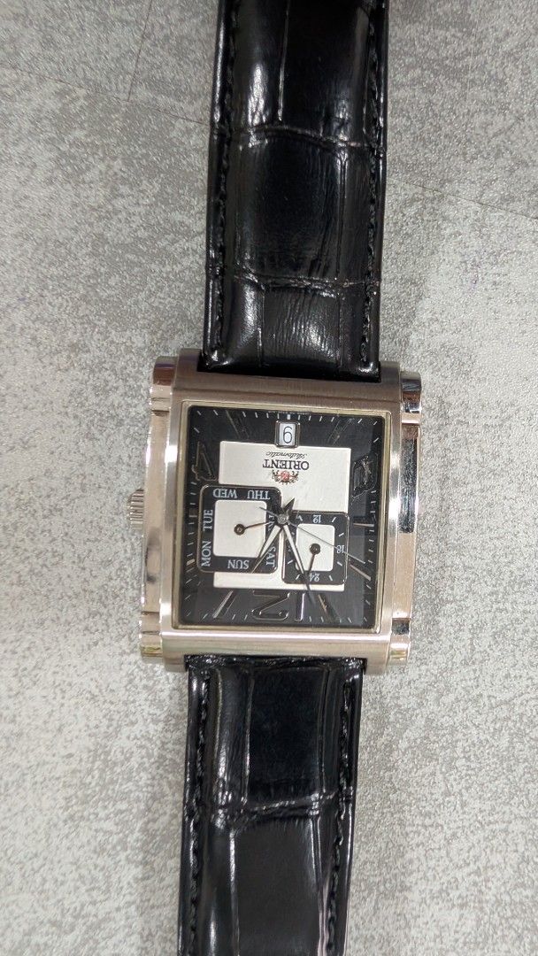 Orient Rectangular Dial Watch (Category: Watches) located in Simpang. Submitted by mohidza (Listing ID 1437474984, Image 1). Description: - Orient rectangular watch -Automatic - Black dial - Day and date display - Silver-tone case - Black crocodile-pattern leather strap - Buckle clasp - Orient logo on the back.