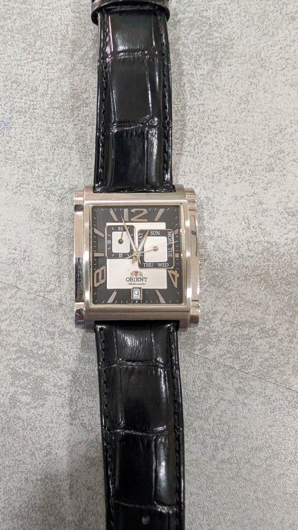 Orient Rectangular Dial Watch (Category: Watches) located in Simpang. Submitted by mohidza (Listing ID 1437474984, Image 2). Description: - Orient rectangular watch -Automatic - Black dial - Day and date display - Silver-tone case - Black crocodile-pattern leather strap - Buckle clasp - Orient logo on the back.
