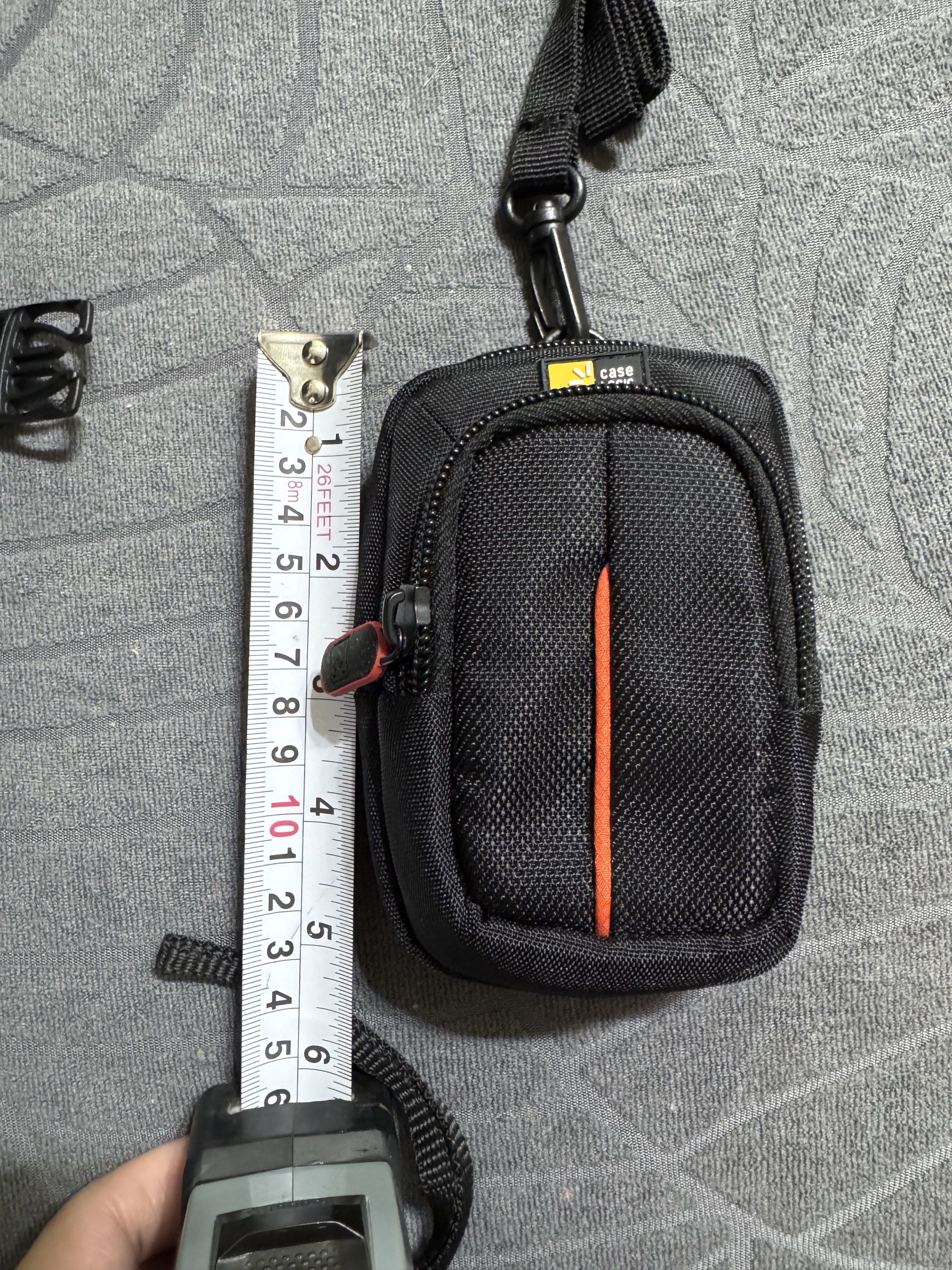 Original Case Logic Camera Case Pouch with Strap (Category: Camera Bags & Carriers) located in Manila. Submitted by milleshoppppp (Listing ID 1437558842, Image 2). Description: - Case Logic camera case - Never been used (as the strap is still tied) - Sizes are indicated in the photo - Black exterior with orange stripe - Red zipper accent - Detachable strap included - Gray interior - Made in Cambodia - Small size, ideal for compact cameras or acce