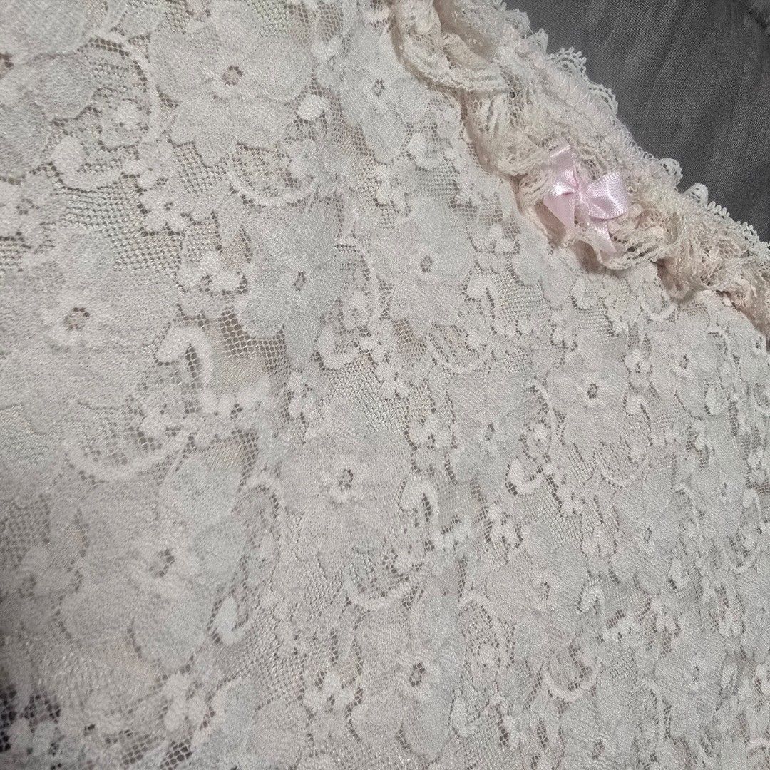 Pink Floral Lace Top (Category: Sleeveless) located in Adams. Submitted by declutter.seasonnn (Listing ID 1437411777, Image 2). Description: - Light pink lace top - Asymmetrical design - Single shoulder strap - Small bow detail - Ruffled trim - Lightweight and semi-sheer fabric - Perfect for layering.