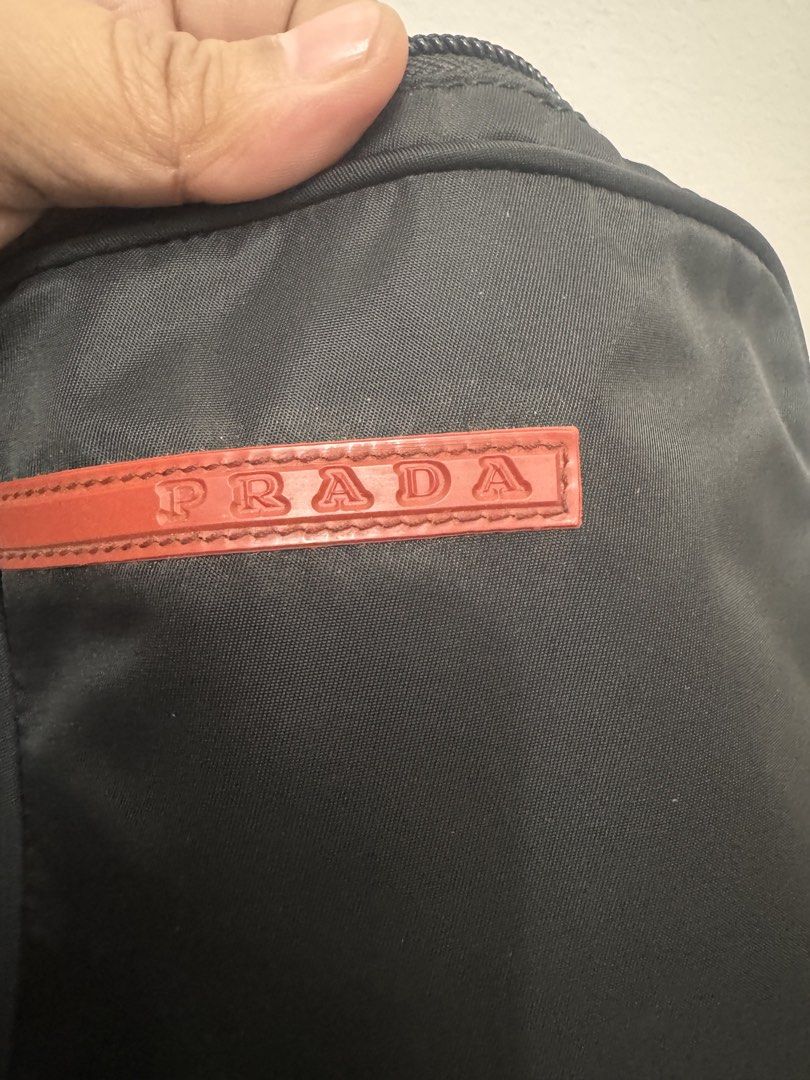 Prada Black Messenger Bag (Category: Luxury Bags & Wallets) located in Koronadal. Submitted by milagraciaukayukay123_. (Listing ID 1437556318, Image 3). Description: - Authentic Prada messenger bag - Classic black nylon material - Iconic red Prada logo - Secure zip closure - Adjustable strap for comfortable wear - Interior tag with serial number 7 - Ideal size for daily essentials.