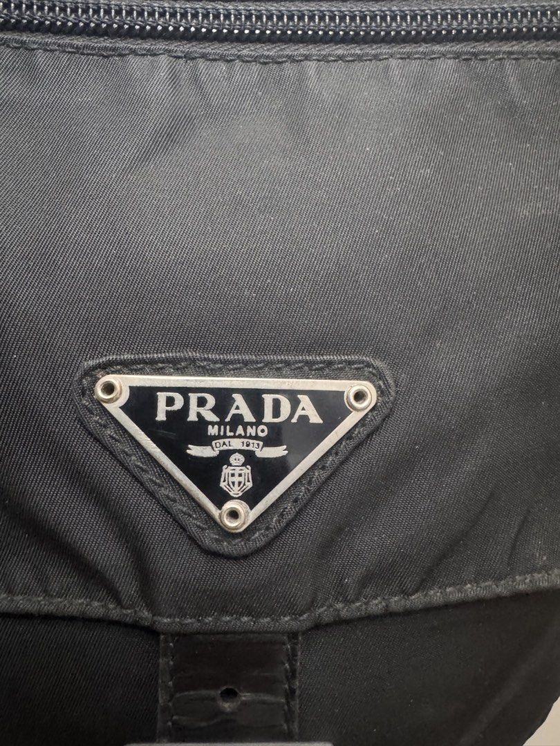 Prada Black Nylon Messenger Bag (Category: Luxury Bags & Wallets) located in Koronadal. Submitted by milagraciaukayukay123_. (Listing ID 1437556537, Image 2). Description: - Authentic Prada messenger bag - Black nylon material - Flap closure with buckle - Front zip pocket - Adjustable shoulder strap - Prada logo detail - Interior with patterned lining - Zip closure inside - Features "LAMPO" zippers.
