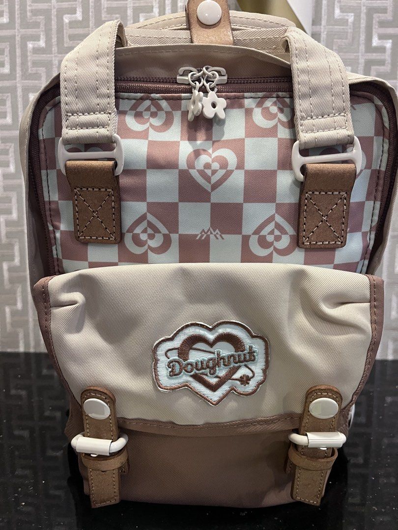 Doughnut Macaron Mini Kaliedo Series Backpack (Category: Backpacks) located in Pasig City. Submitted by jackiedla (Listing ID 1437656472, Image 2). Description: - Original Doughnut Mini backpack - Mushroom Checked Color - Front pocket with Doughnut logo - Adjustable straps - Top handle - Brand new with tags - Color: Beige, brown, and pink.