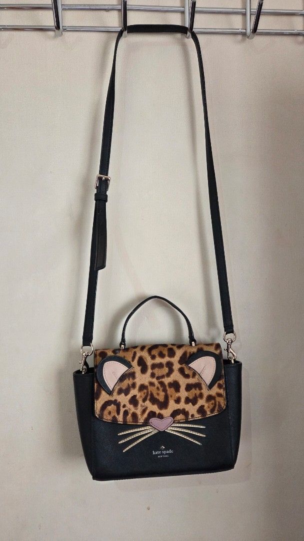 Kate Spade Cat Crossbody Bag (Category: Luxury Bags & Wallets) located in Davao. Submitted by noona.nette (Listing ID 1437624178, Image 2). Description: - Kate Spade crossbody bag - Unique cat design - Leopard print flap - Embroidered whiskers - Top handle and adjustable strap - Black with silver-tone hardware - Compact size.