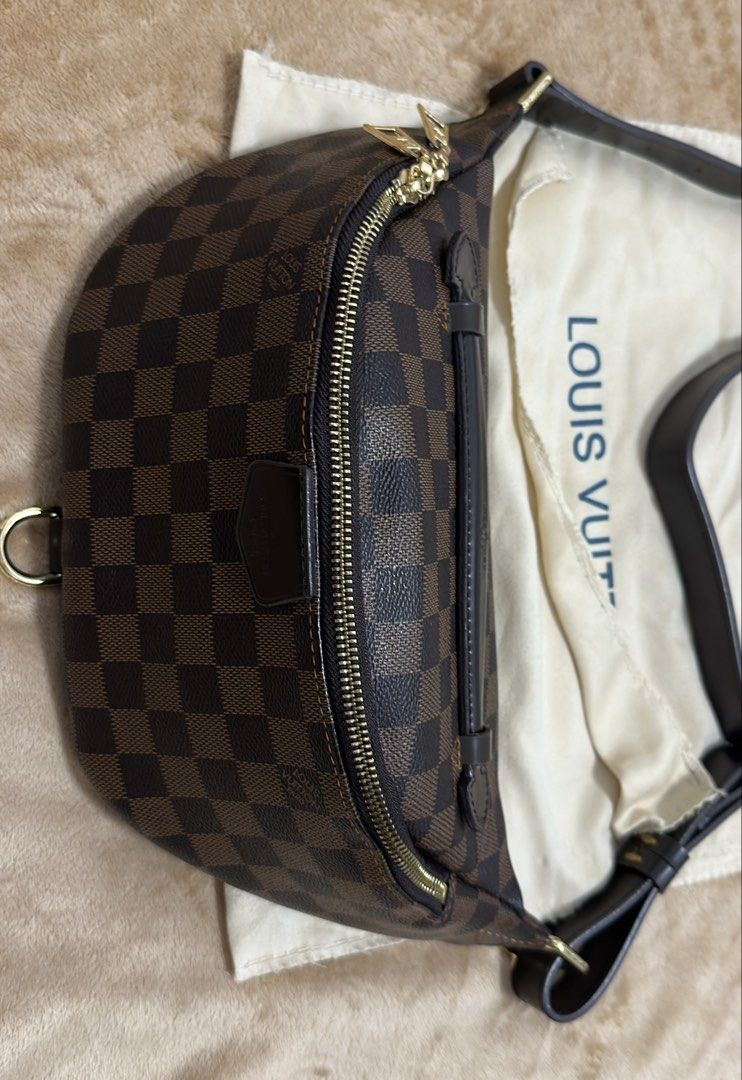 Louis Vuitton Damier Ebene Bumbag (Category: Luxury Bags & Wallets) located in Manila. Submitted by savilaaa (Listing ID 1437692060, Image 2). Description: - Preloved Louis Vuitton Bumbag - Product Code - Damier Ebene canvas - Gold-tone hardware - Adjustable brown leather strap - Includes dust bag - Classic checkerboard pattern - Features Louis Vuitton logo patch.