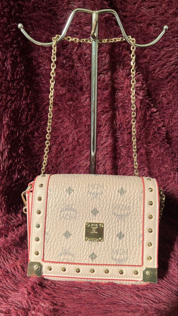 MCM Crossbody Bag with Chain Strap (Category: Luxury Bags & Wallets) located in Muntinlupa City. Submitted by armendaber03743 (Listing ID 1437737099, Image 1). Description: - MCM Crossbody Bag - Chain strap and flap closure - Signature MCM logo pattern - Light pink exterior with red trim - Gold-tone hardware and studded details - Includes a small gold plaque with the MCM logo - Features a serial number.