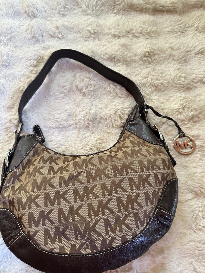 Michael Kors Shoulder Bag (Category: Luxury Bags & Wallets) located in Digos. Submitted by venusacaro13427 (Listing ID 1437591050, Image 2). Description: - Authentic Michael Kors shoulder bag - Iconic MK logo print - Stylish curved design - Brown leather accents - Matching shoulder strap - Branded interior lining - Interior zippered pocket - Silver-tone hardware - Includes Michael Kors logo charm.