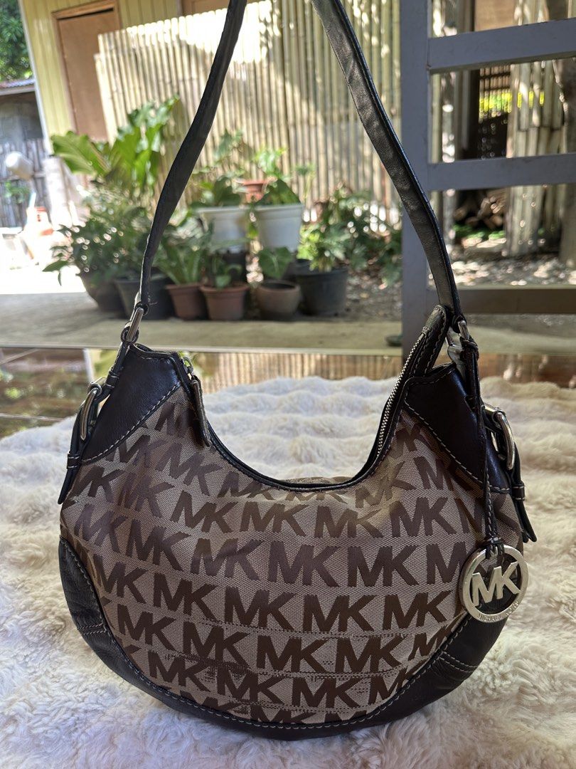 Michael Kors Shoulder Bag (Category: Luxury Bags & Wallets) located in Digos. Submitted by venusacaro13427 (Listing ID 1437591050, Image 1). Description: - Authentic Michael Kors shoulder bag - Iconic MK logo print - Stylish curved design - Brown leather accents - Matching shoulder strap - Branded interior lining - Interior zippered pocket - Silver-tone hardware - Includes Michael Kors logo charm.