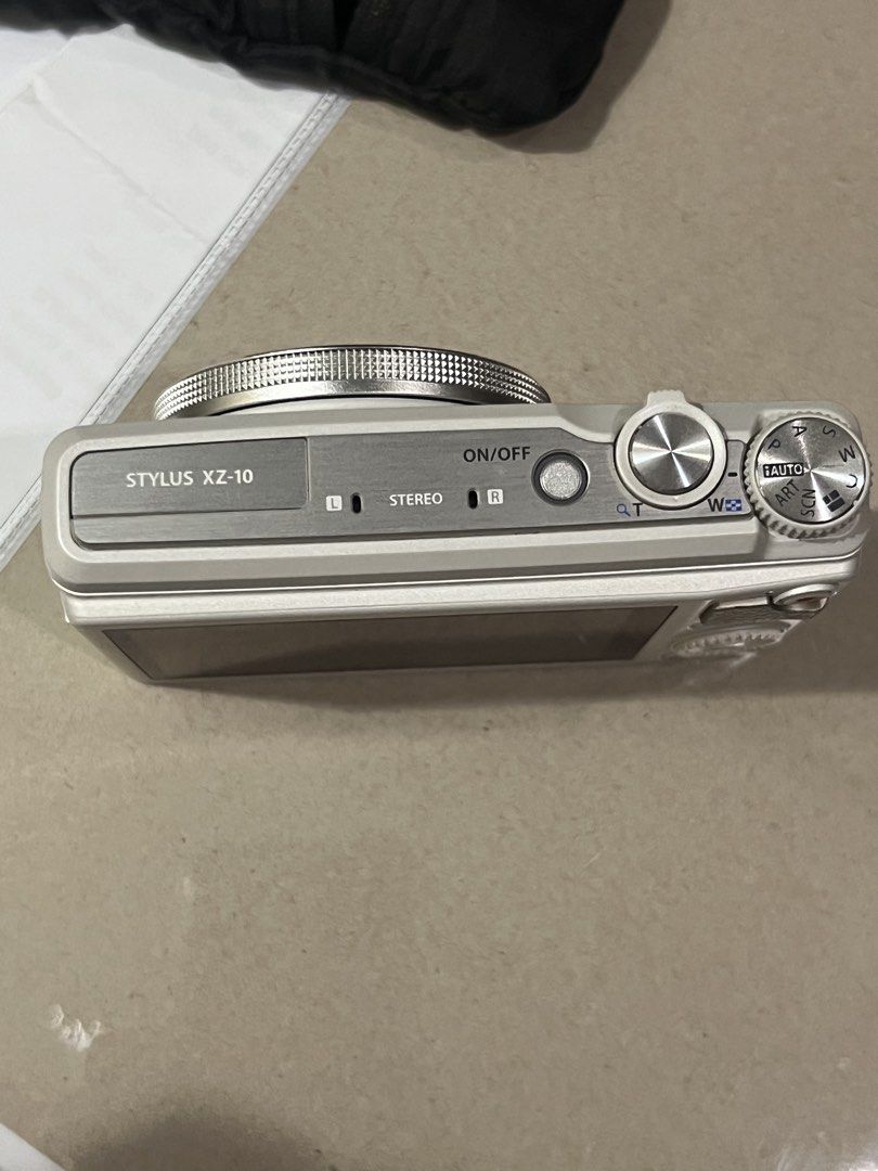 Olympus Stylus XZ-10 Digital Camera (Category: Cameras) located in Caloocan City. Submitted by olivelemon (Listing ID 1437684440, Image 2). Description: - Olympus Stylus XZ-10 digital camera - Zoom lens - Built-in flash - White body with silver accents - Stereo microphone - On/off switch NO CHARGER - Shooting mode dial - Lens inscription: "ZUIKO DIGITAL".