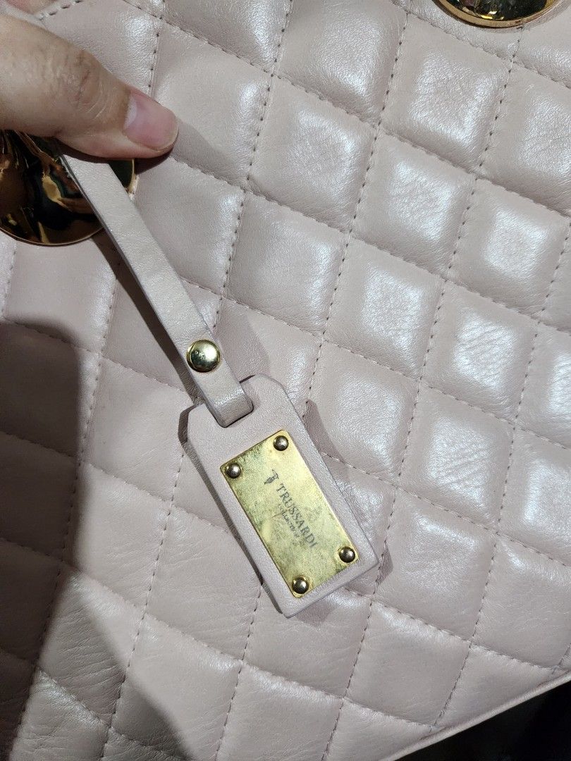 Trussardi Quilted Handbag (Category: Luxury Bags & Wallets) located in Makati City. Submitted by itsgonnabemay (Listing ID 1437703713, Image 2). Description: Elegant Trussardi handbag in a quilted design. Can be a crossbody bag and hand bag. Features a light pink color with gold-tone hardware. Includes a top handle and a detachable shoulder strap. The bag has a rectangular shape with a flap closure. The Trussardi logo is visible on a small tag at