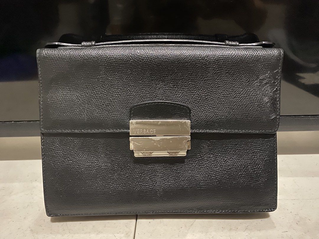 Versace Black Trifold Flap Leather Envelope (Category: Luxury Bags & Wallets) located in Manila. Submitted by resi.diaz (Listing ID 1437724653, Image 1). Description: - Bought from Surplus. - Not professionally authenticated. - Sold as is. - Top handle design - Front clasp closure with Versace branding - Textured leather exterior - Iconic Medusa head logo - Convenient back zippered pocket.