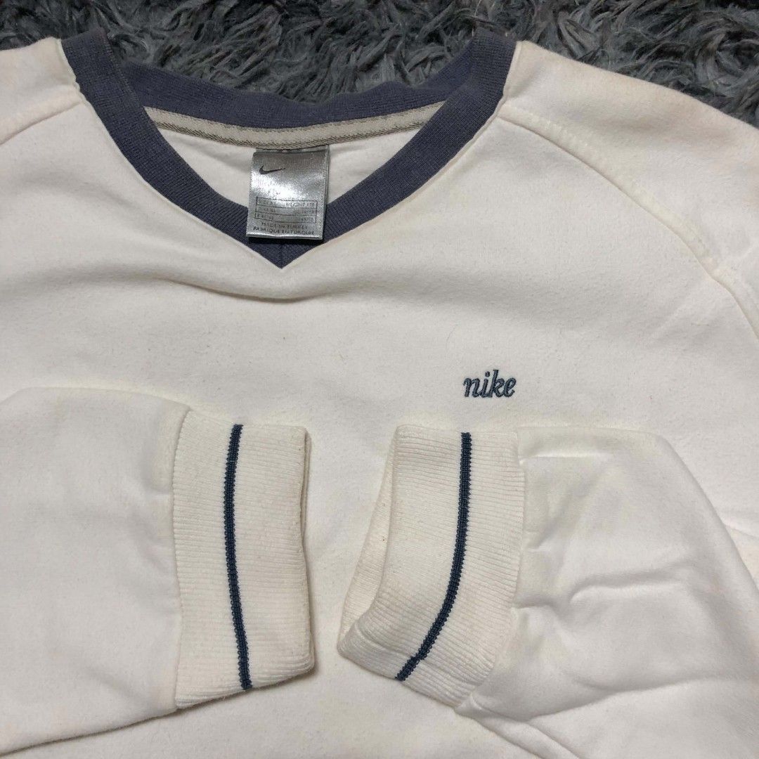 Vintage Nike V-Neck Sweatshirt (Category: Coats, Jackets and Outerwear) located in Cavite. Submitted by autothrift (Listing ID 1437604579, Image 2). Description: - White Nike V-neck sweatshirt - Small Nike logo on chest - Navy blue accents on collar and cuffs - Brand and size tag included - Classic and comfortable fit.