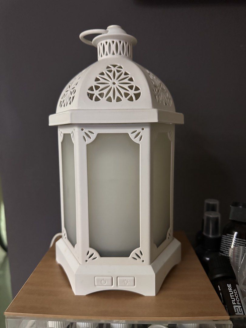 White Lantern Diffuser (Category: Other Home Decor) located in Seri Kembangan. Submitted by luxeforlessbysm (Listing ID 1437706602, Image 1). Description: - Elegant white lantern design - Decorative top and frosted panels - Includes power button and another button - Suitable for essential oils - Comes with a power cord - Perfect for adding style and fragrance to any room.